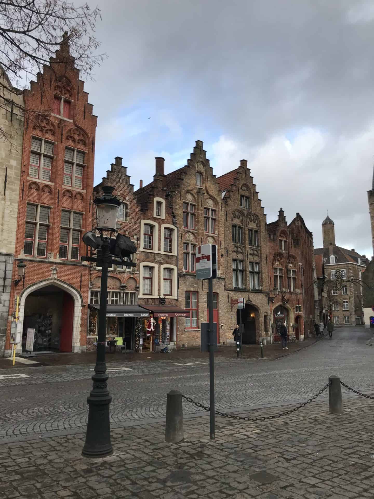 European brick buildings with a cobblestone road in front and a cast iron street lamp.