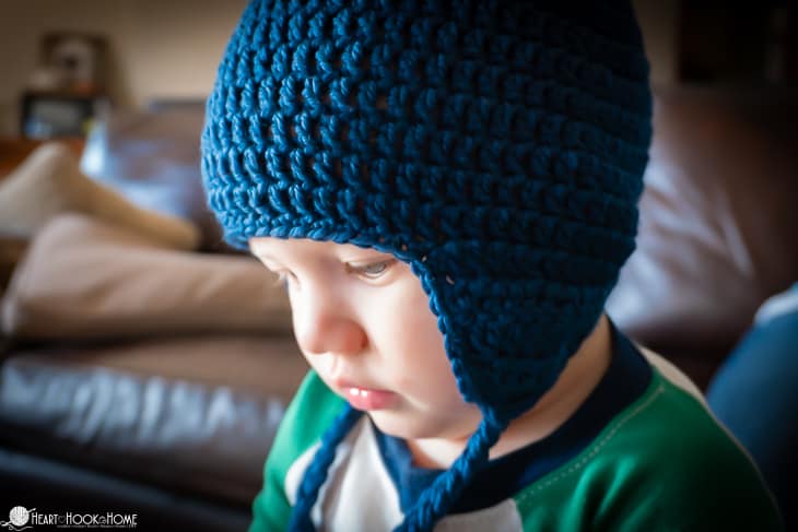 Cute baby wearing a a blue beanie with ear flaps.