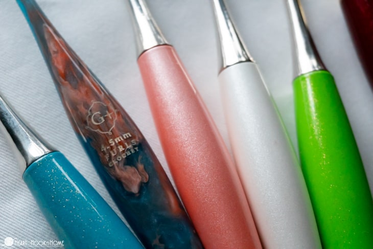 The Furls Streamline Swirl G+, 4.5mm crochet hook in a swirled pink and blue color along with solid blue, pink, white, and green crochet hooks.