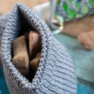 Gray colorway of an example of the Dog Treat Bag crochet pattern with dog treats peaking out.