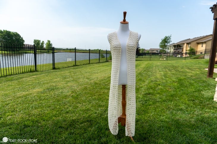 Ivory colorway of the Easy Breezy Lightweight Summer Vest crochet pattern on a dress form in a grassy yard.