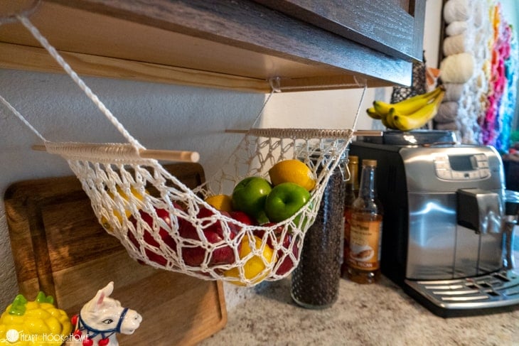 Fruit Hammock crochet pattern with multiple fruits hanging under a cabinet. 