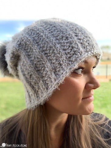 Female model looking off into the distance wearing a white example of the Heavenly Hygge Hat Tunisian Crochet Pattern.