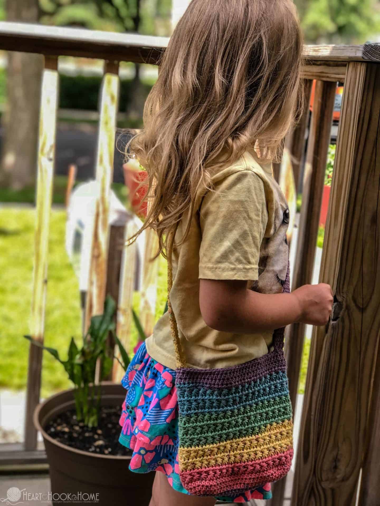 Multicolored Child Size Purse crochet pattern being held by a small female child.