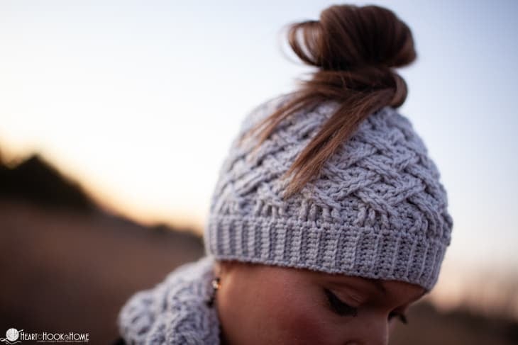 Gray example of the Messy Bun version of the Lattice Love Beanie crochet pattern on a female model.