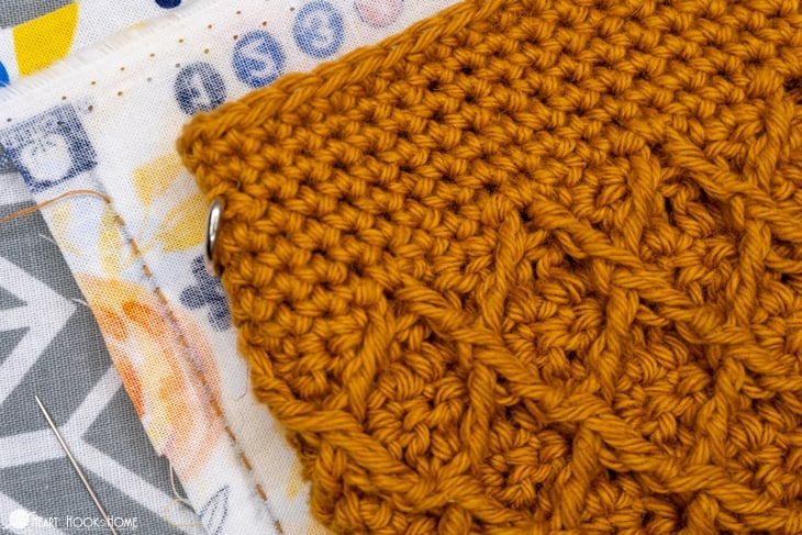 Gold colorway example of the Girl\'s Best Friend Crossbody Purse crochet pattern laid on top of a flowery fat quarter lining.