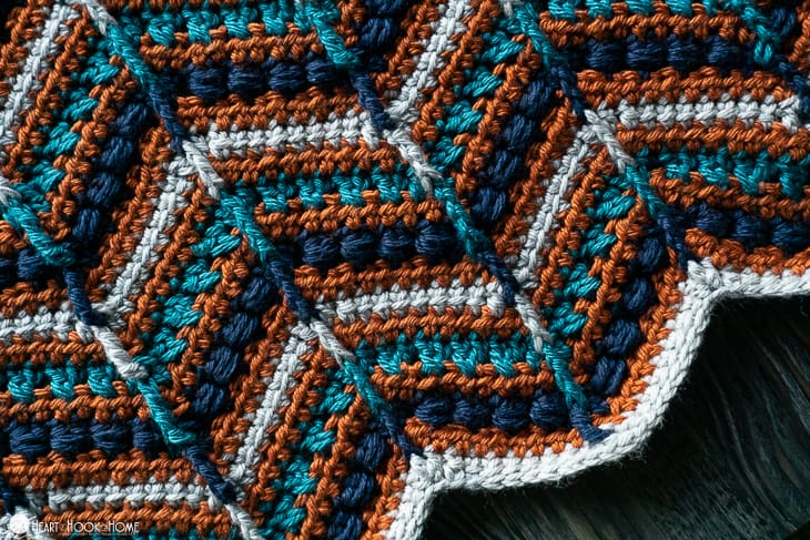 Example of Mae's Chevron Crochet Blanket pattern in Gloss DK (in colorways Masala, Robot, Kenai, and Navy).
