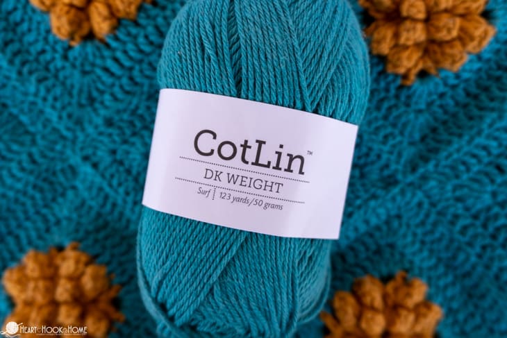 CotLin yarn skein in the Surf colorway sitting on samples of the Marigold Sling Bag crochet pattern.