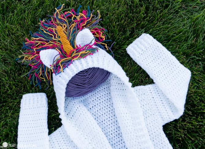 Sample of the Painted Canyon Cardigan crochet pattern with a gold unicorn horn, unicorn ears, and rainbow hair.