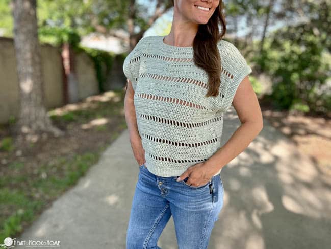 Open stitch style Godiva Tee on a female model wearing jeans in a park.