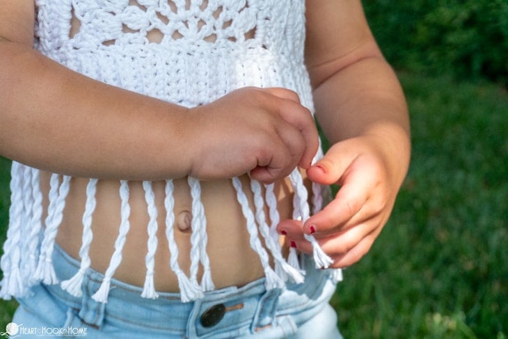 White Twisted Fringe added to the end of a Toddler Boho Halter Top crochet pattern on a small child.