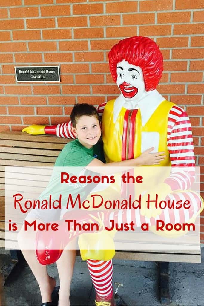 Male child sitting and hugging a Ronald McDonald statue.