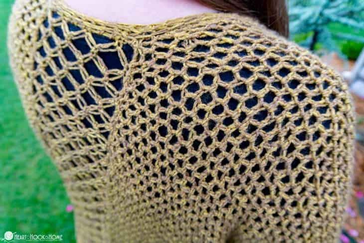 Gold example of the shoulder area of the Come On I Ruana crochet pattern over a black shirt.