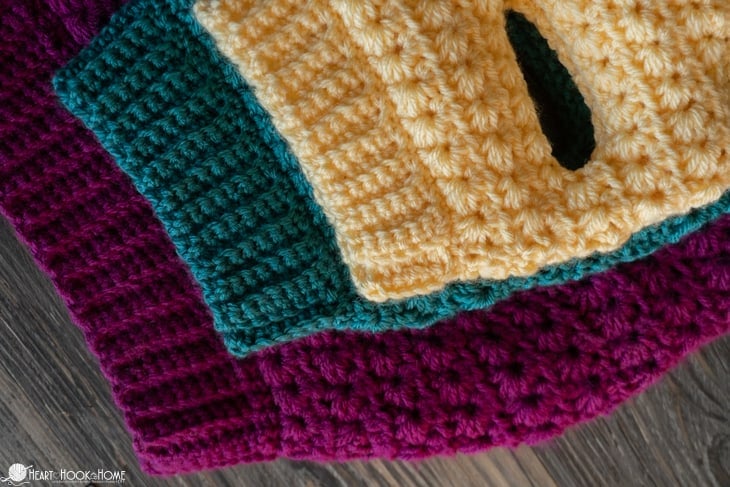 Purple, blue and yellow examples of three sizes of the Stellar Dog Sweater crochet pattern.