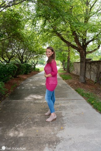 Example of the Summer Sultan Cardi crochet pattern in the Cerise colorway of CotLin yarn from WeCrochet on a smiling female model in a park setting.