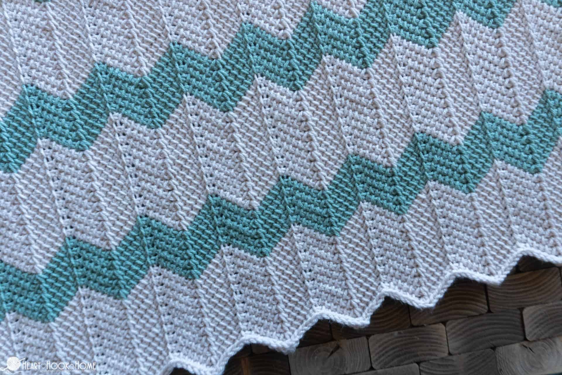 White and sage colored example of a Tunisian Chevron Baby Blanket crochet pattern.