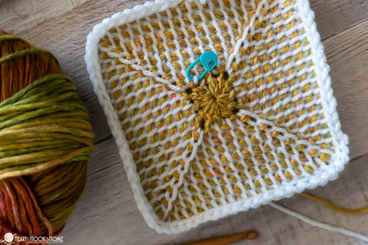 Gold and white example of the Tunisian Crochet Granny Square with a blue stitch marker.