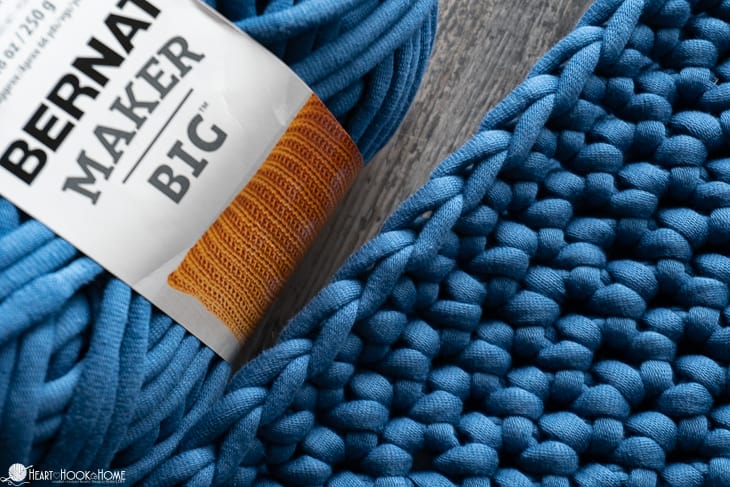 Blue Bernat Maker Big skein of yarn next to a sample of the Outdoor Chair Cushion Cover crochet pattern.