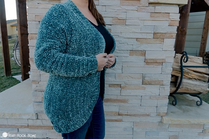 Frosted Pine colorway example of the Velvet Cardi Crochet Pattern on a female model standing in front of a brick wall.
