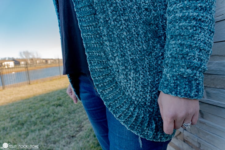 Frosted Pine colorway example of the Velvet Cardi Crochet Pattern on a female model standing near a pond.