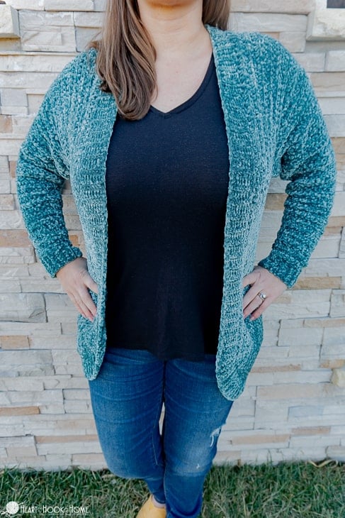 Frosted Pine colorway example of the Velvet Cardi Crochet Pattern on a female model standing in front of a brick wall.