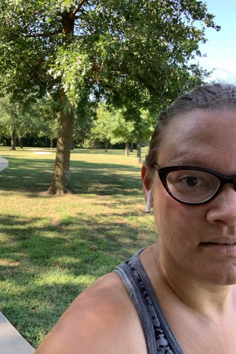 Female wearing Ear Pods standing in a park setting.