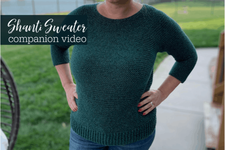 Example of a green version of a Shanti Sweater Crochet Pattern on a female model wearing jeans and standing in a backyard setting.