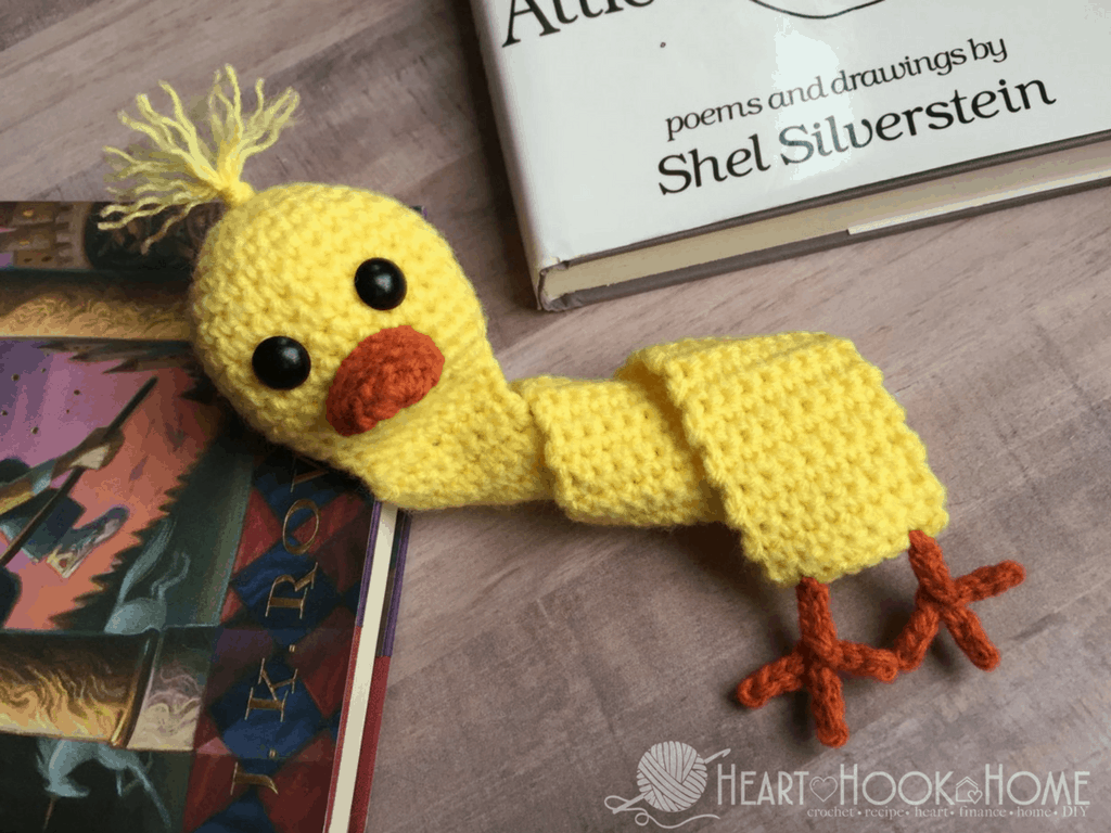 Yellow example of the Quacktastic Duck Bookmark crochet pattern near a couple of books.