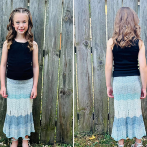 child wearing blue crocheted skirt against fence
