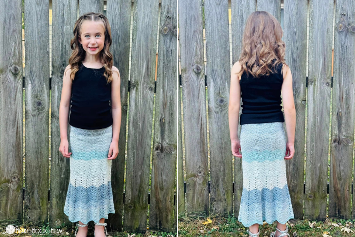 child wearing blue crocheted skirt against fence
