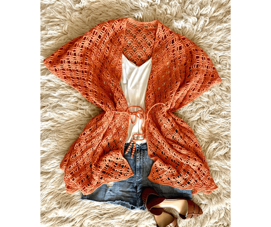 Maddie Ruana in a Coral color, paired with a white tank top, jean shorts and brown shoes.