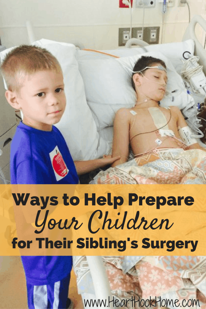Small child holding the arm of a male sibling post heart surgery and still hooked up to monitors in a hospital bed.
